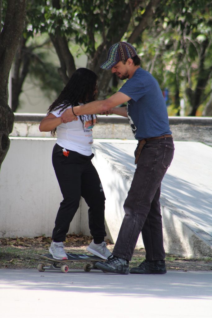 Aidé ariba de la patineta es apoyada por un miembro de la Fakie School.